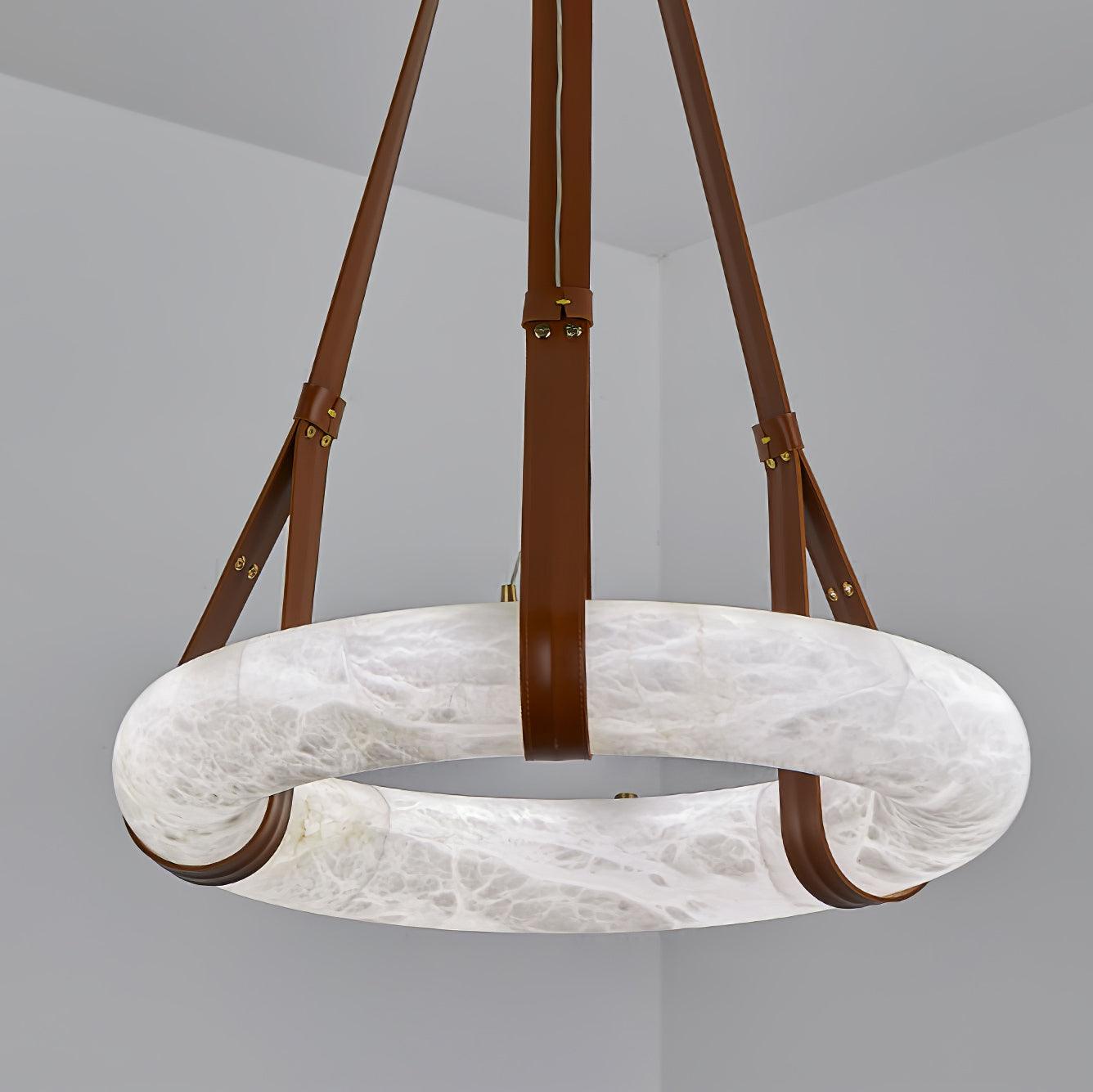 Clérachic Alabaster Ring Pendant Light seen from below on brown leather straps, the flat stone hoop filling the corner of the room.