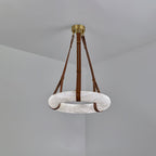 Clérachic Alabaster Ring Pendant Light hung in a grey corner, brown straps running from the brass canopy to the unlit stone ring.