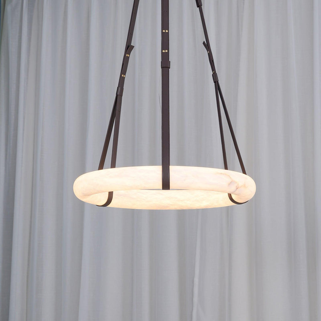 Clérachic Alabaster Ring Pendant Light switched on before a sheer white curtain, the whole band turning warm from the inside.