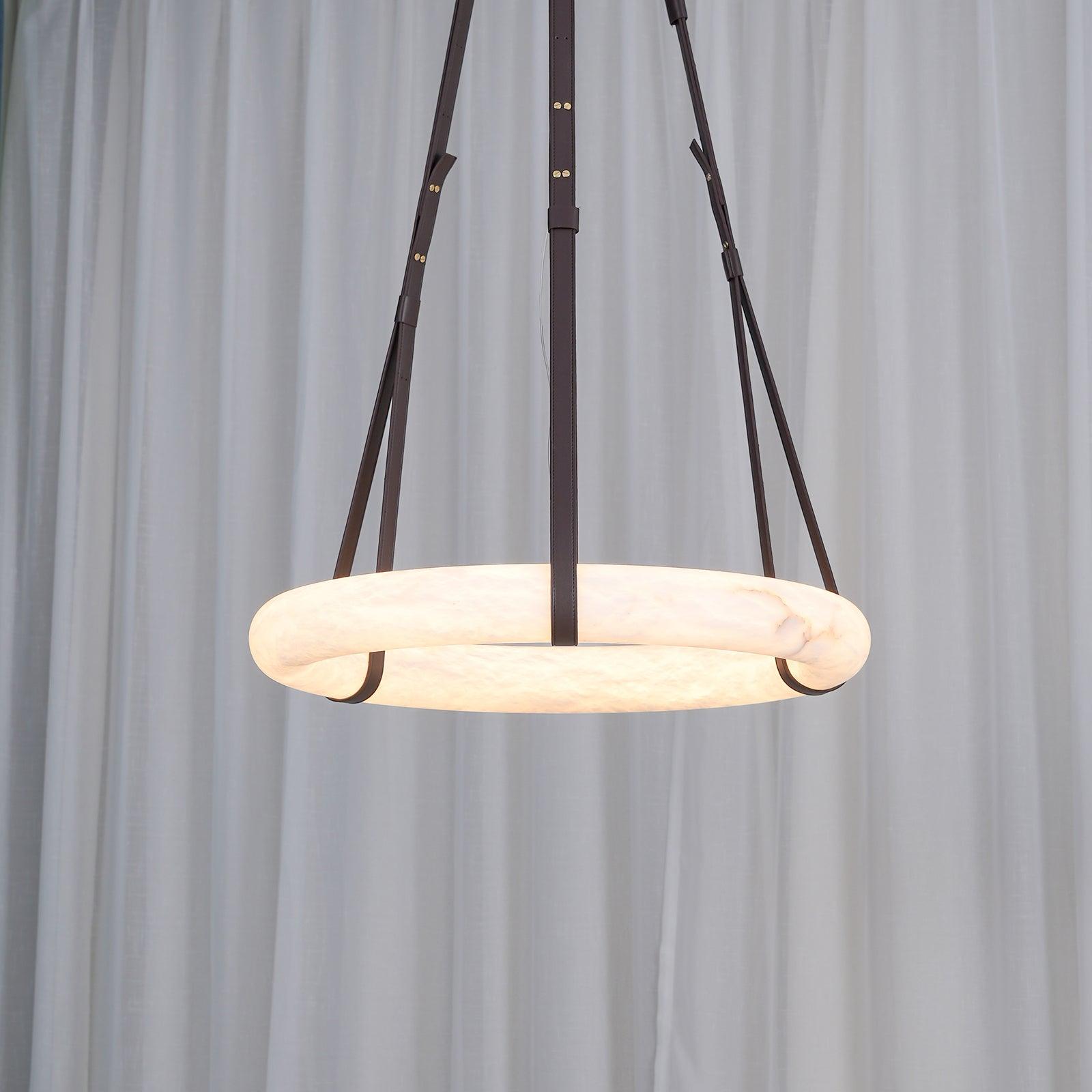 Clérachic Alabaster Ring Pendant Light switched on before a sheer white curtain, the whole band turning warm from the inside.