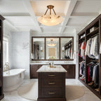 This Clérachic alabaster ceiling light hangs in a dressing room with a freestanding bath, a marble floor and a dark wood island.