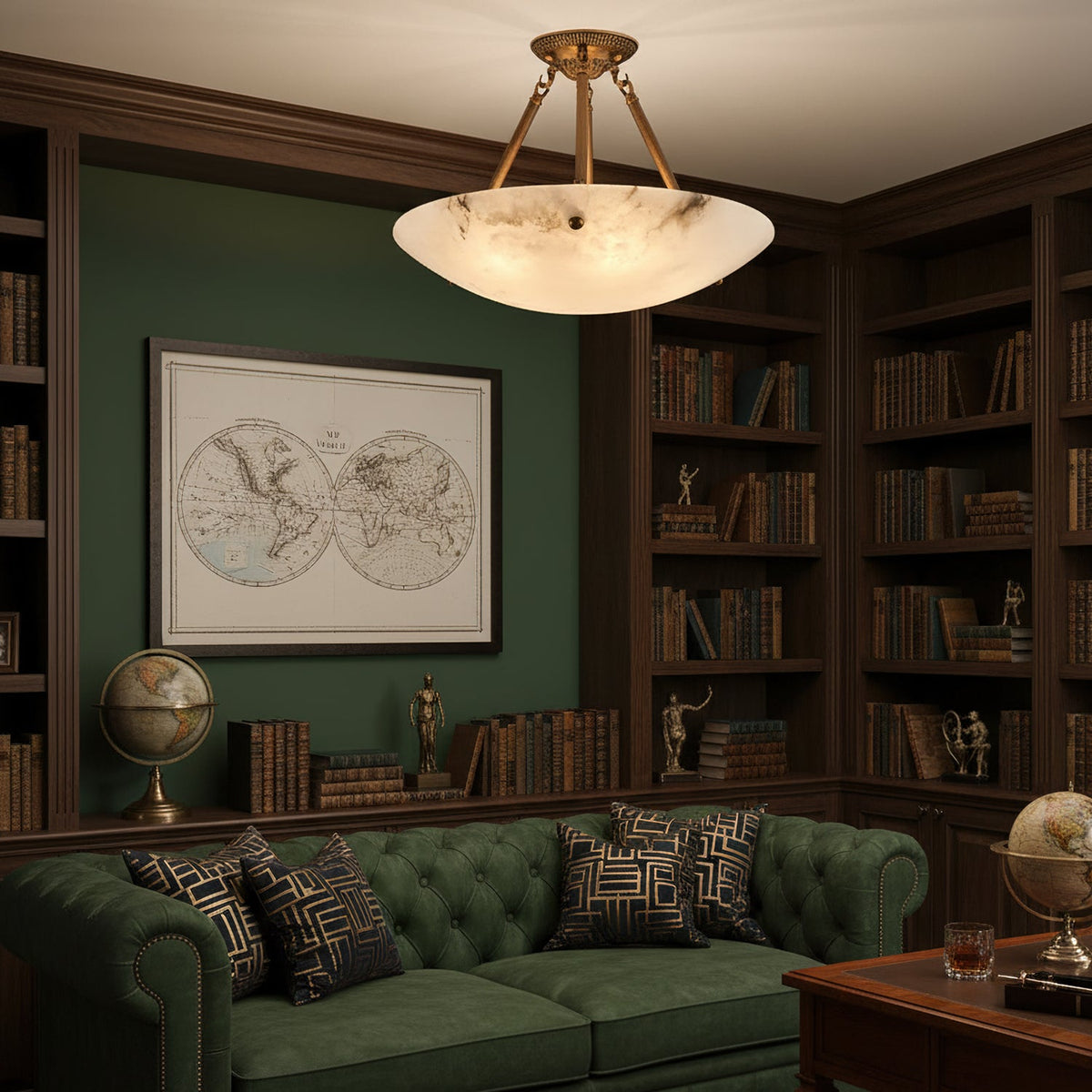 A Clérachic alabaster bowl light hangs in a library with green walls, wooden bookcases and a tufted green sofa.