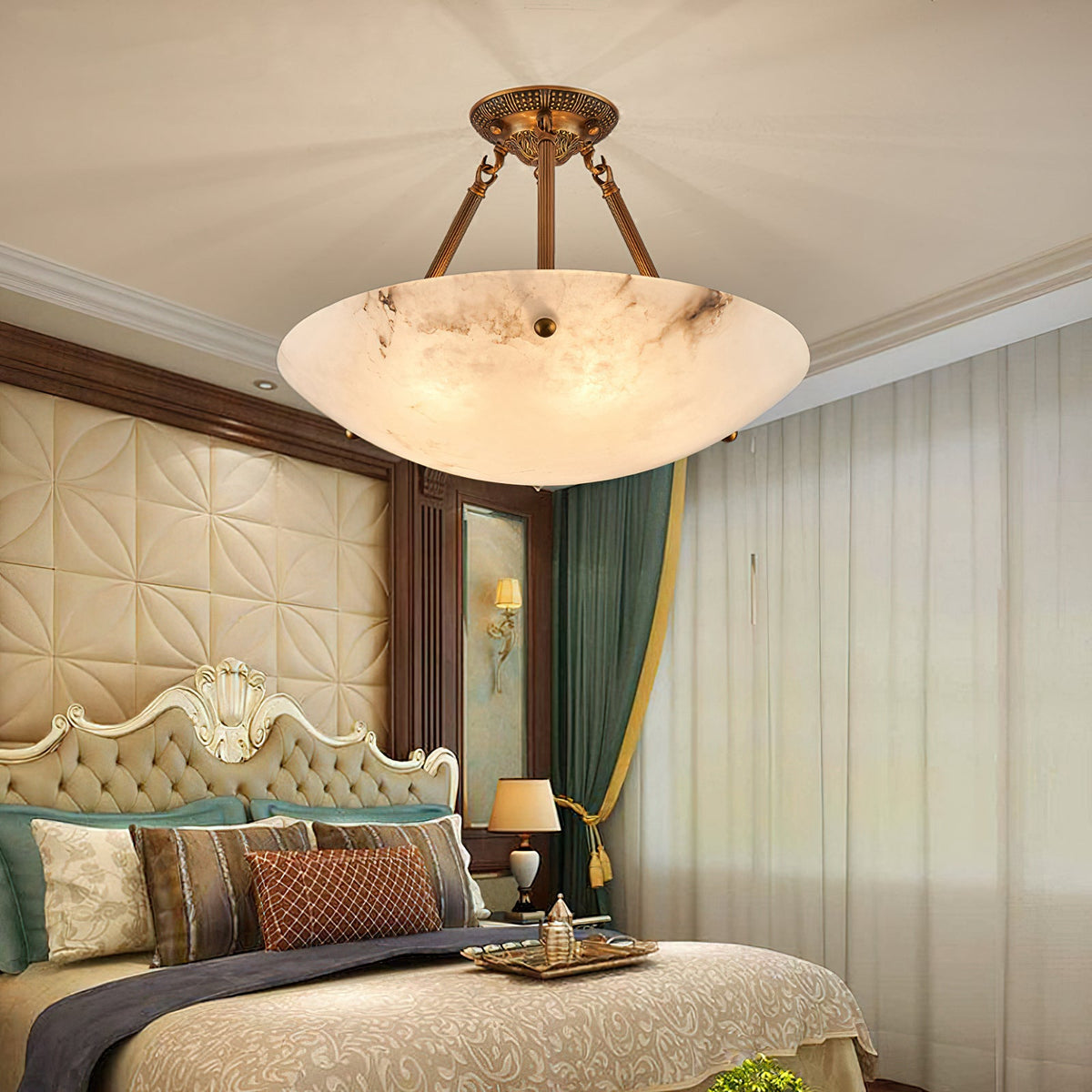 This Clérachic alabaster bowl light glows above a bed with a quilted headboard, teal and copper cushions and a green curtain.