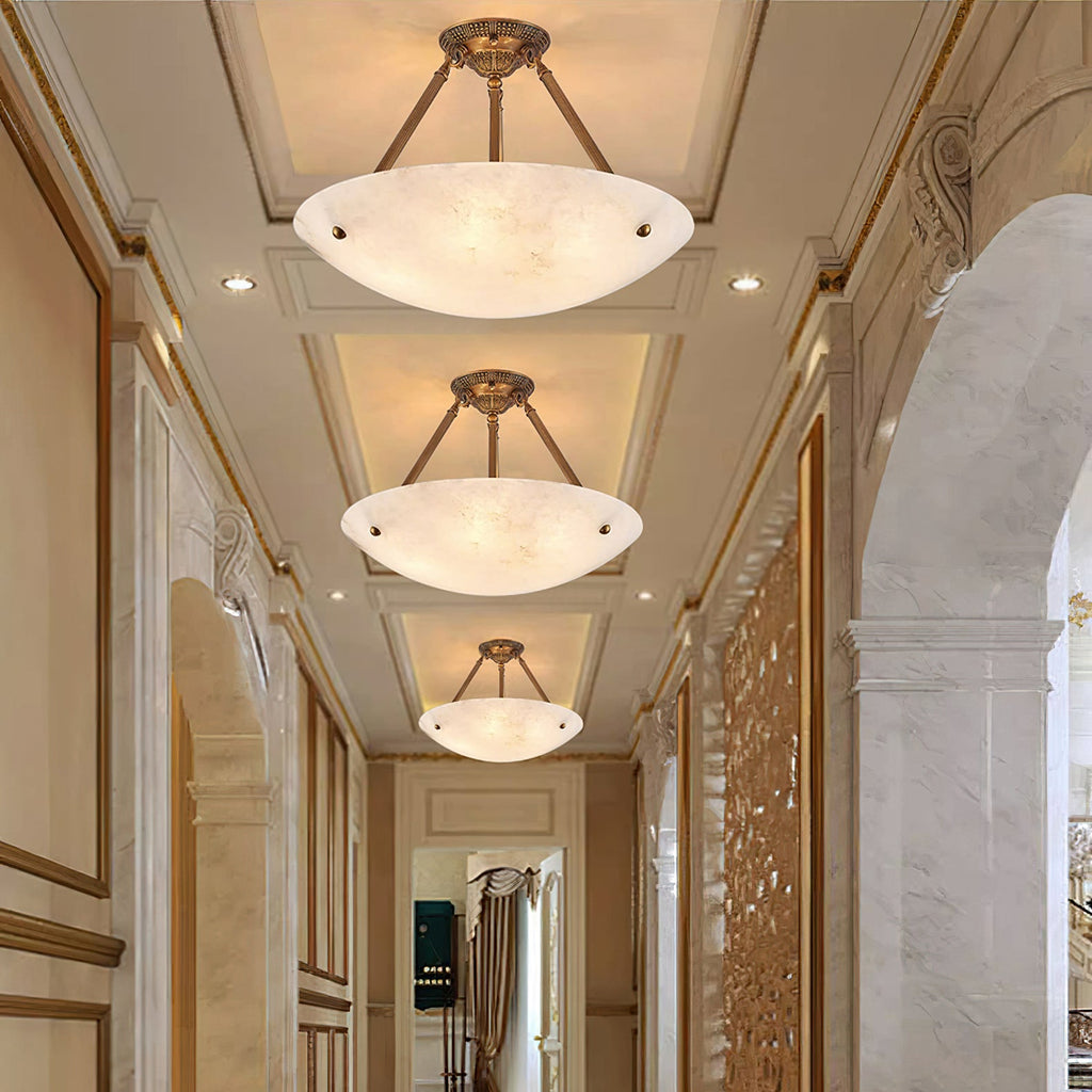 Three Clérachic alabaster bowl lights line a long panelled hallway, each hung from antique brass arms.