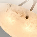 Close view of the glowing alabaster bowl, its dark veining and a small brass stud, on this Clérachic ceiling light.