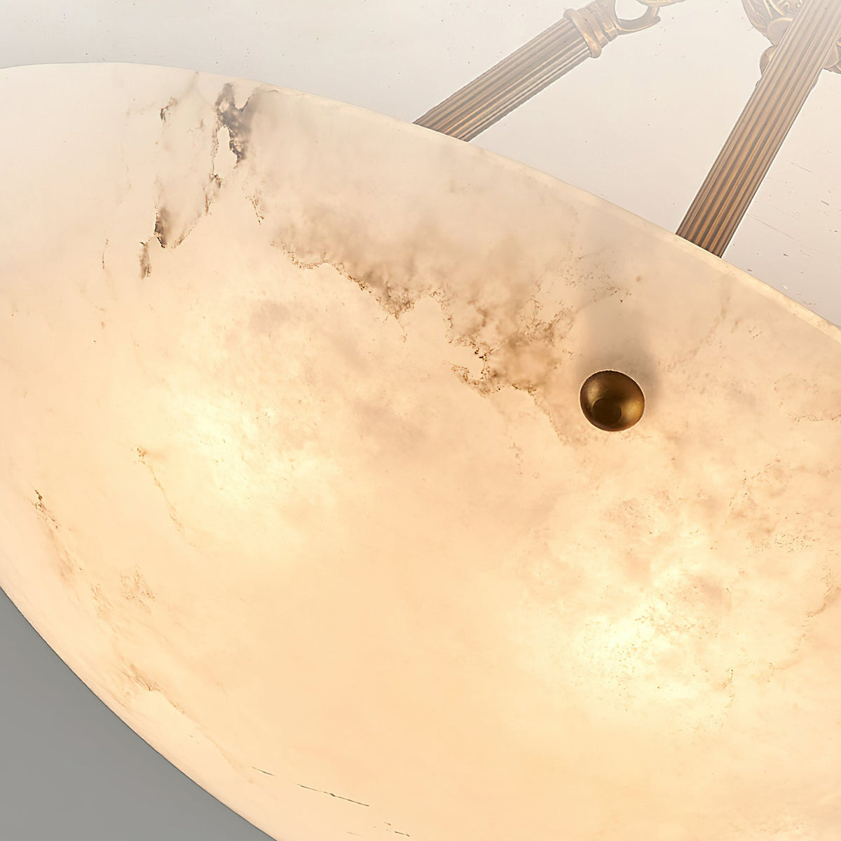 Close view of the glowing alabaster bowl, its dark veining and a small brass stud, on this Clérachic ceiling light.