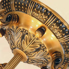 Close view of the embossed antique brass canopy, with leaf-pattern casting and ribbed arms, on this Clérachic ceiling light.