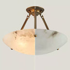 A split view of this Clérachic alabaster bowl light, lit and warm on the left, unlit and cool white on the right.