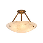 A Clérachic alabaster bowl light on white, lit warm, with a short antique brass stem and three ribbed arms.