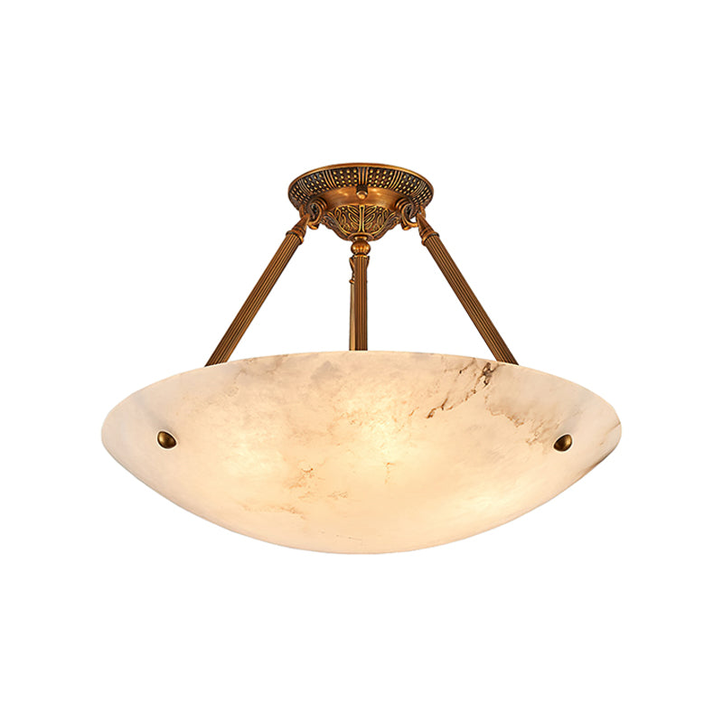A Clérachic alabaster bowl light on white, lit warm, with a short antique brass stem and three ribbed arms.