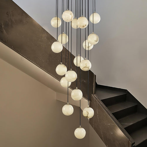 Clérachic alabaster spheres drop at different heights past a dark marble stair wall, each glowing a soft white.