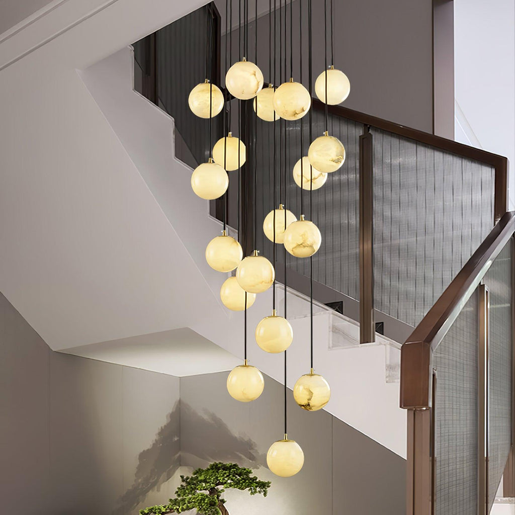 Close view of the Clérachic alabaster spheres lit warm, hanging beside a walnut stair rail with mesh panels and a small bonsai below.