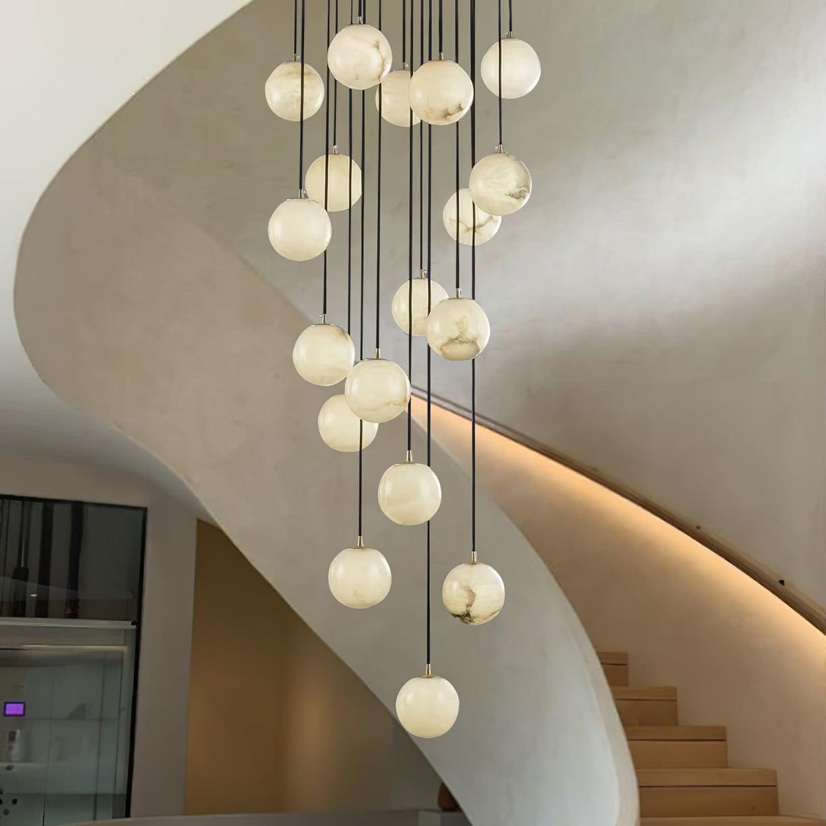 Clérachic alabaster spheres in a tall curved stairwell, with a warm light strip tracing the edge of the stair below.