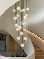 Clérachic alabaster spheres hang inside a curved plaster stair, with a glowing light line along the wall and a few green leaves below.