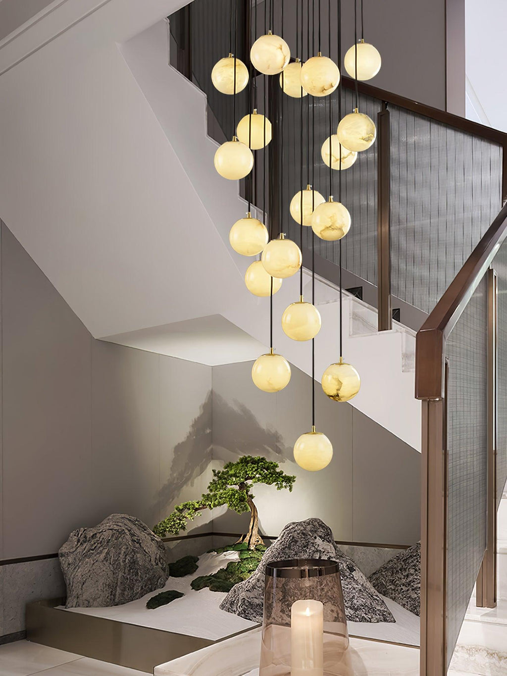 Clérachic alabaster spheres descend past a walnut rail with mesh panels, above a small rock and bonsai garden at the foot of the stair.