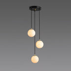 Three lit Clérachic alabaster spheres hang at different heights from a round black canopy against a grey gradient backdrop.