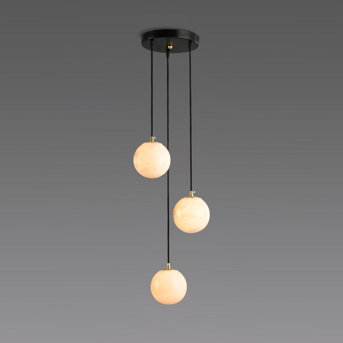 Three lit Clérachic alabaster spheres hang at different heights from a round black canopy against a grey gradient backdrop.