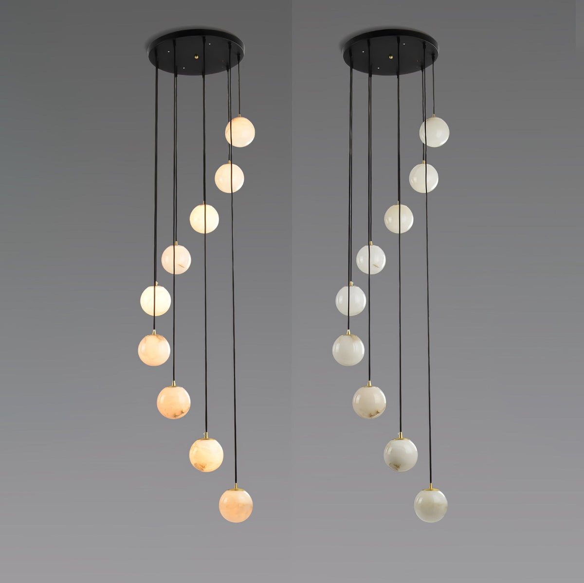 Two Clérachic sphere pendants side by side on grey, the spheres stepping down in a spiral, one warm in tone and one pale.