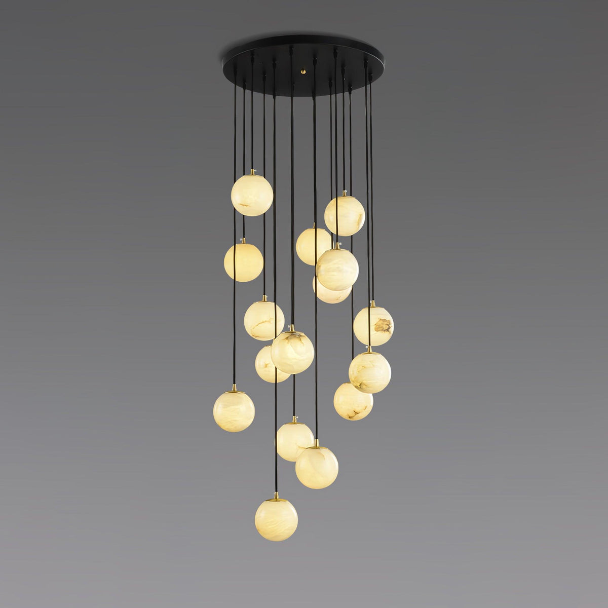 Clérachic cluster of lit alabaster spheres on black cords from a round canopy, shown against a grey gradient backdrop.