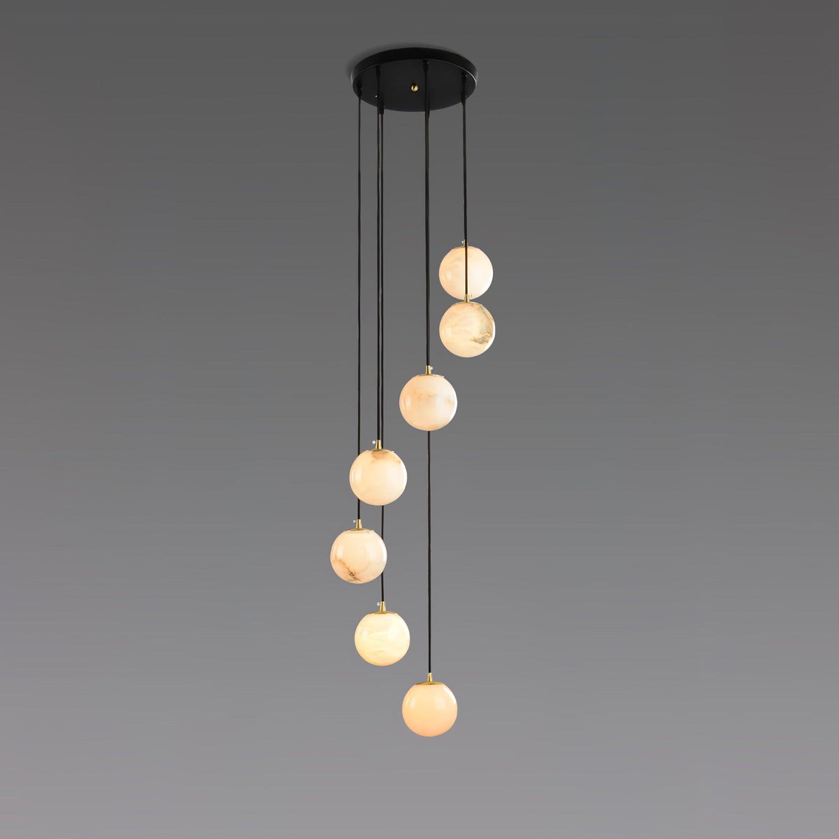 Six warm alabaster spheres from Clérachic hang from a round black canopy on a grey backdrop.