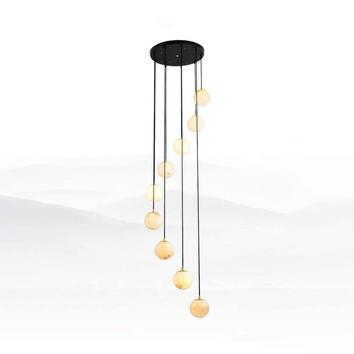 Slim run of Clérachic alabaster spheres in a tall spiral on long black cords, against a pale mist-landscape backdrop.
