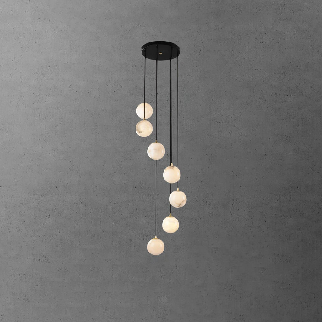 Eight Clérachic alabaster spheres hang in a loose spiral from a black canopy, in front of a grey concrete-effect wall.