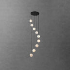 Long Clérachic alabaster sphere spiral, slim and tall, hanging from a round black canopy on a grey textured wall.