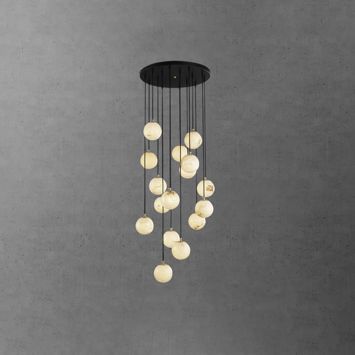 Dense Clérachic alabaster sphere cluster, lit pale cream, hanging from a wide round black canopy on a dark grey wall.
