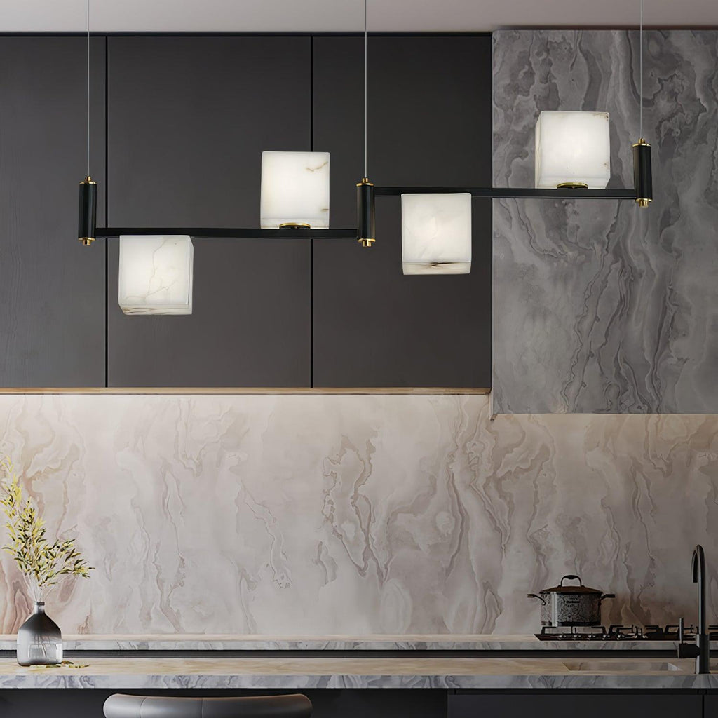 Clérachic box chandelier lit in a dark kitchen against black cabinetry and a marble splashback.
