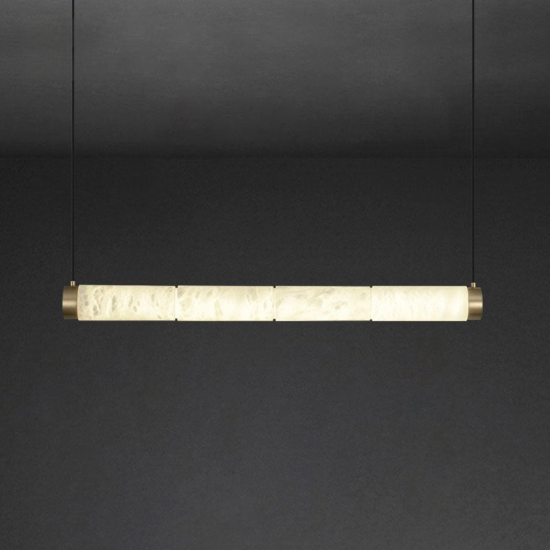 The Clérachic strip pendant at its longest, a wide ribbon of backlit stone closed with brushed brass caps.