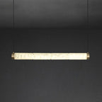 The Clérachic strip pendant at its longest, a wide ribbon of backlit stone closed with brushed brass caps.