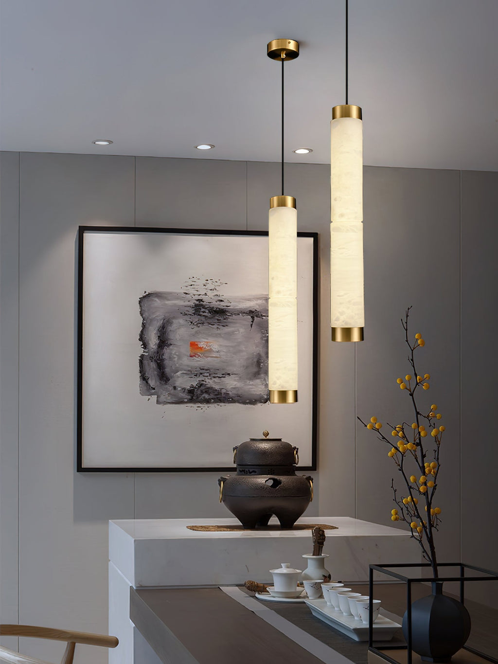 The Clérachic pendants hung at two heights above a pale stone counter, throwing a honeyed glow over a tea set.