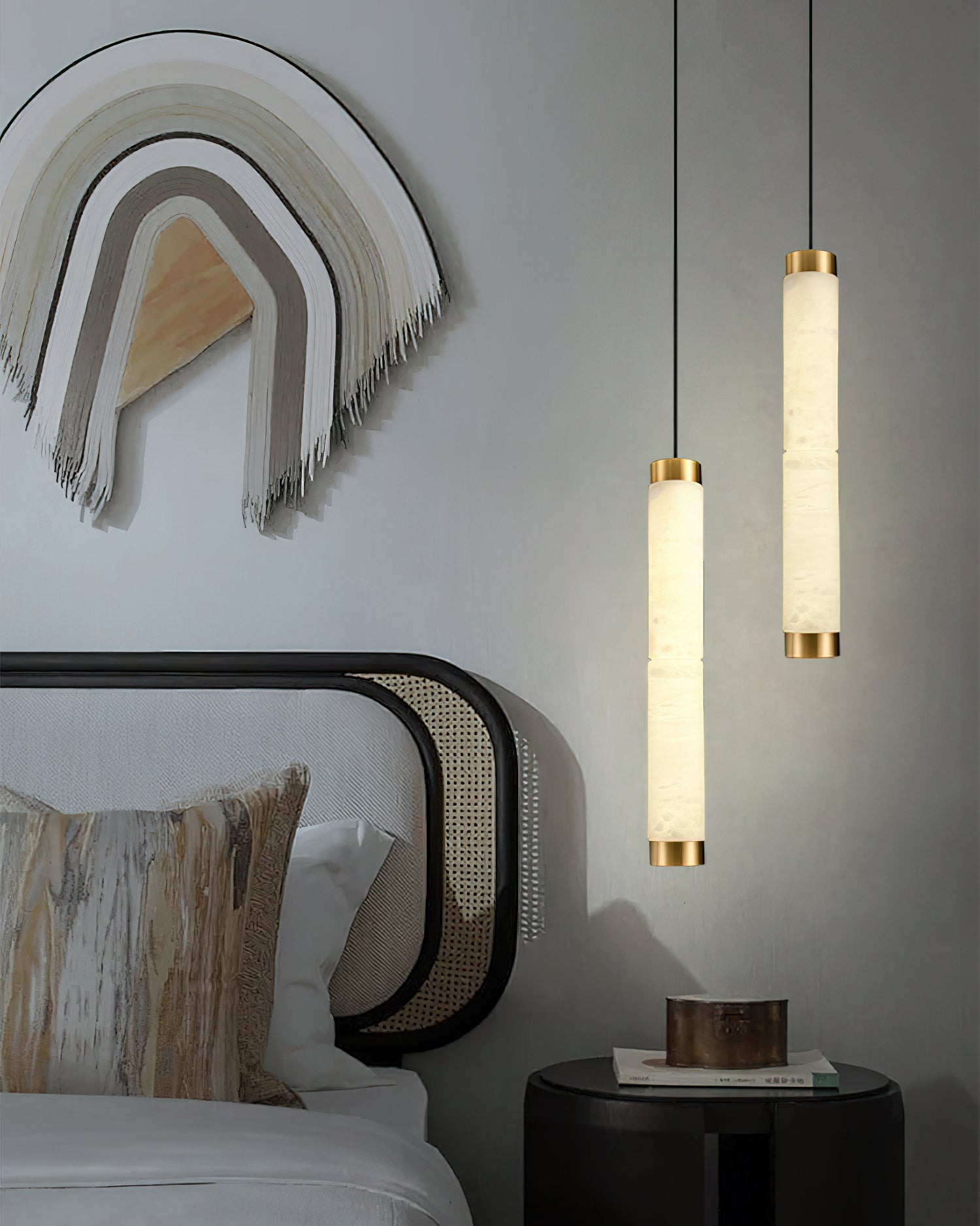 The Clérachic pendants flanking a caned bed, their alabaster columns echoing the warmth of the woven wall hanging.