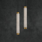The Clérachic pendants staggered at two drops, brass caps catching light against a charcoal plaster wall.