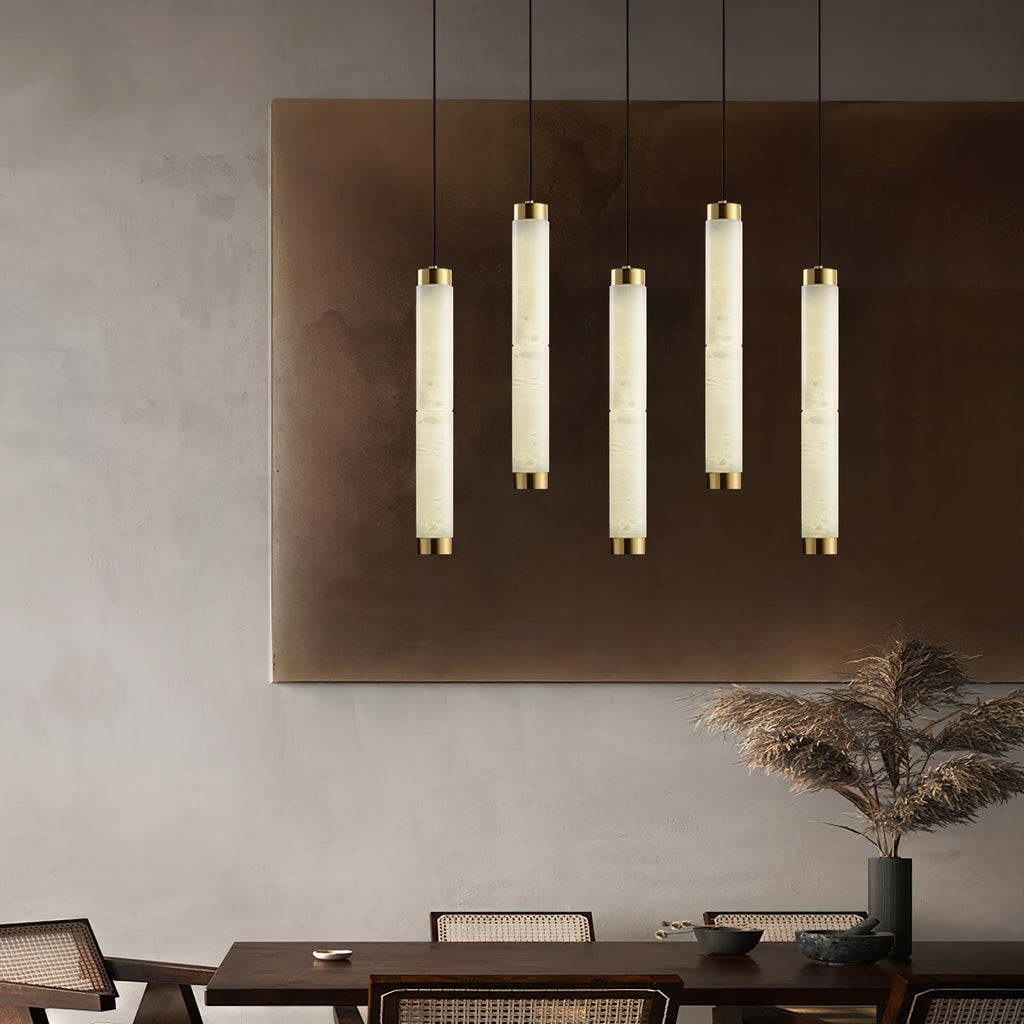 Clérachic pendants hung in a row of five in front of a bronze wall panel above a long dining table.