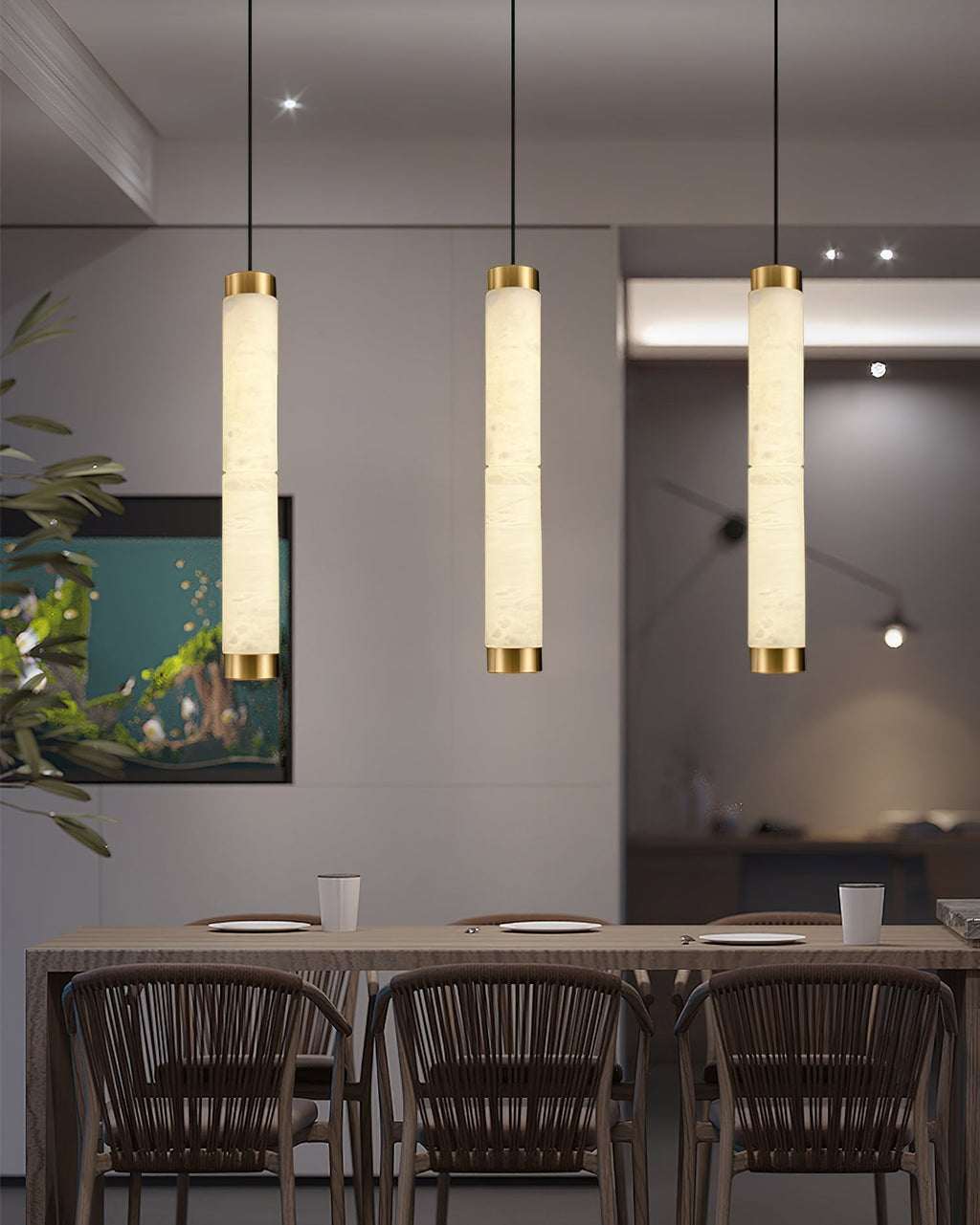 The Clérachic pendants lined up over a dining table, three columns of warm stone light above rattan chairs.