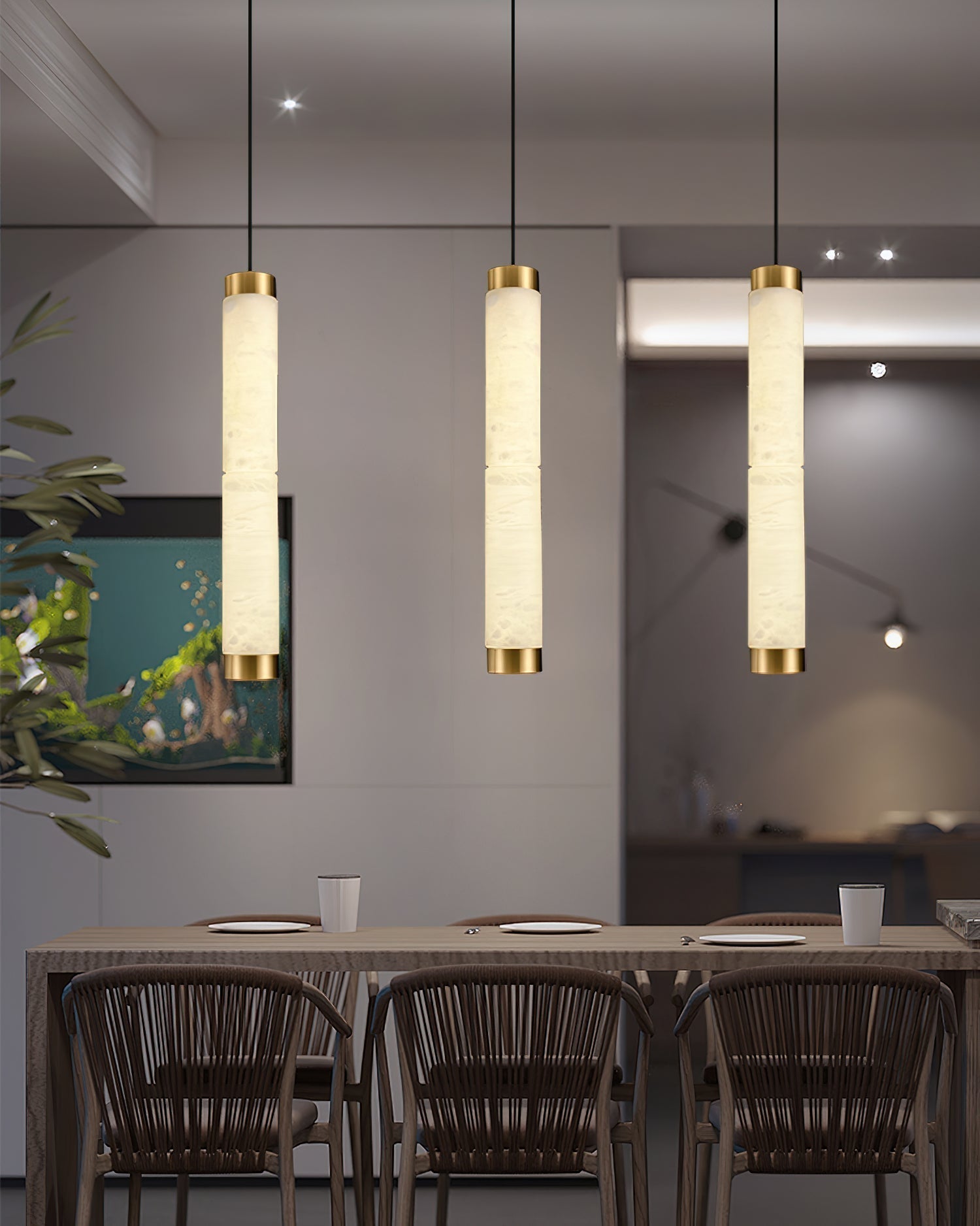 The Clérachic pendants lined up over a dining table, three columns of warm stone light above rattan chairs.
