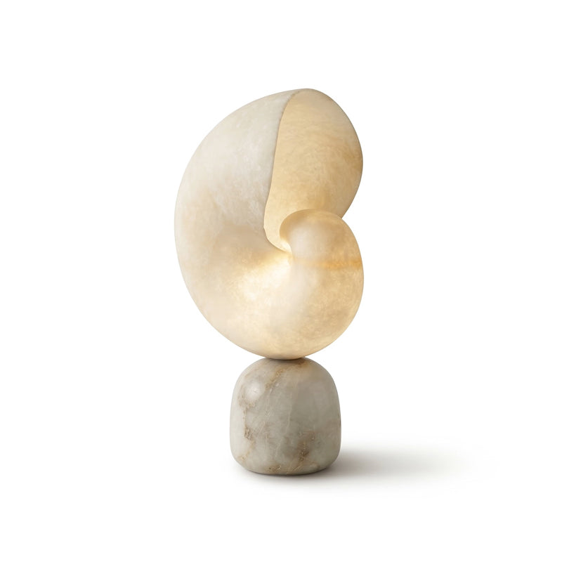 Clérachic alabaster table lamp in an angled view, its spiral shade lit softly on a rounded marbled stone base against white.