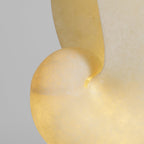 Close view of the spiral edge of the alabaster conch shade on this Clérachic lamp, glowing warm with a cloudy, translucent grain.