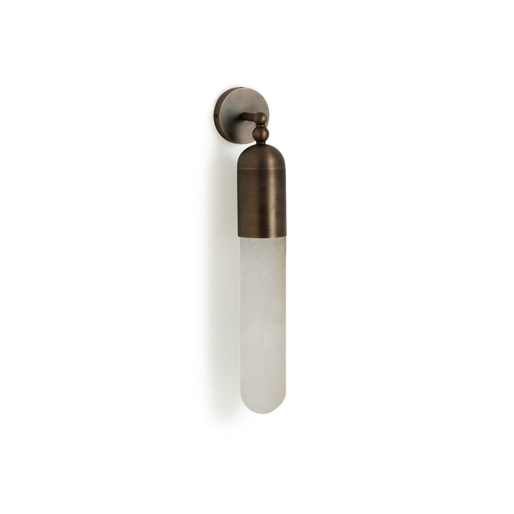 Clérachic Alabaster Tube Wall Sconce mounted on a white wall in antique brass, angled to show the arm's two turned ball joints.