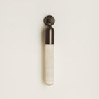 Clérachic Alabaster Tube Wall Sconce in black on a cream wall, unlit, with the grain of the natural alabaster tube visible.