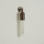 Antique brass Clérachic Alabaster Tube Wall Sconce on a soft grey wall, three-quarter view with its long shadow beside it.