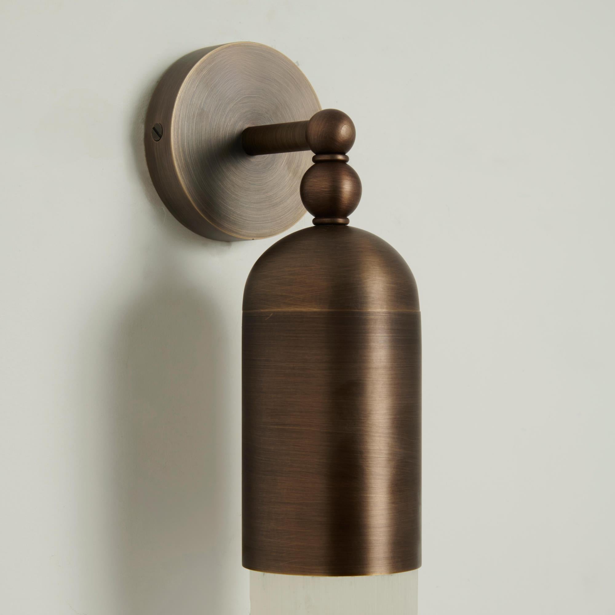 Close-up of the Clérachic Alabaster Tube Wall Sconce's antique brass wall plate, turned ball joints and domed cap.