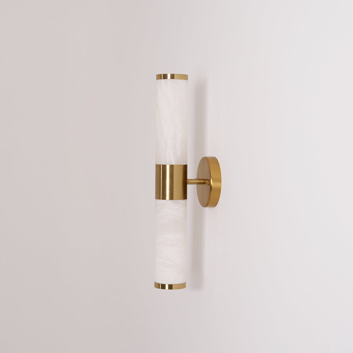 Side view of the unlit Clérachic wall light, with soft grey veining in the white tubes and thin gold rims at each end.