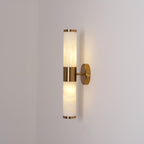Clérachic wall light lit in a corner of a grey room, with both veined tubes glowing and a gold band holding them together.