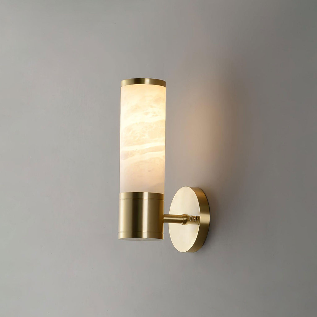 A single veined alabaster tube on a gold collar and short arm, a one-tube Clérachic wall light glowing warmly on a grey wall.