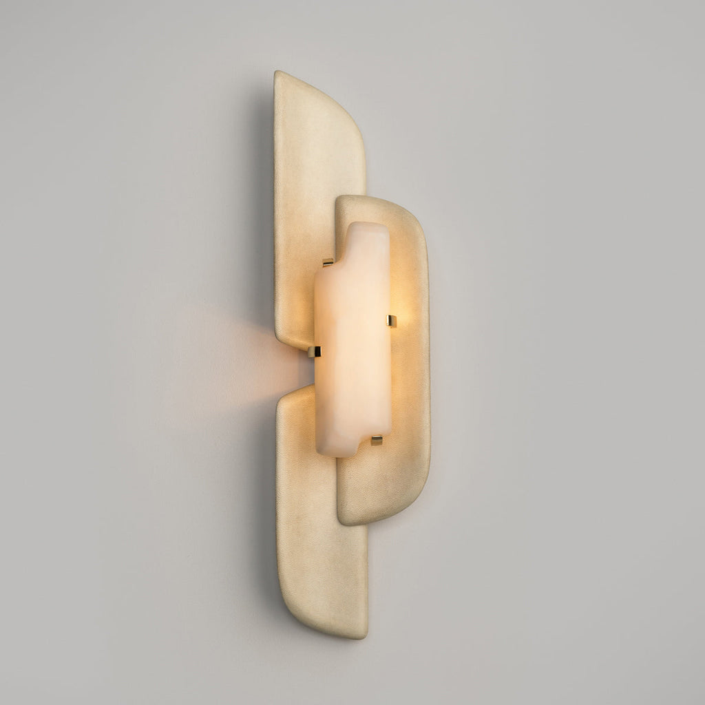 A Clérachic wall lamp with a warm glow through its alabaster panel, and light spilling sideways from the gap between the layers.