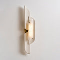 A lit Clérachic wall lamp turned the other way, with a brass bracket visible and a soft shadow cast on the wall.