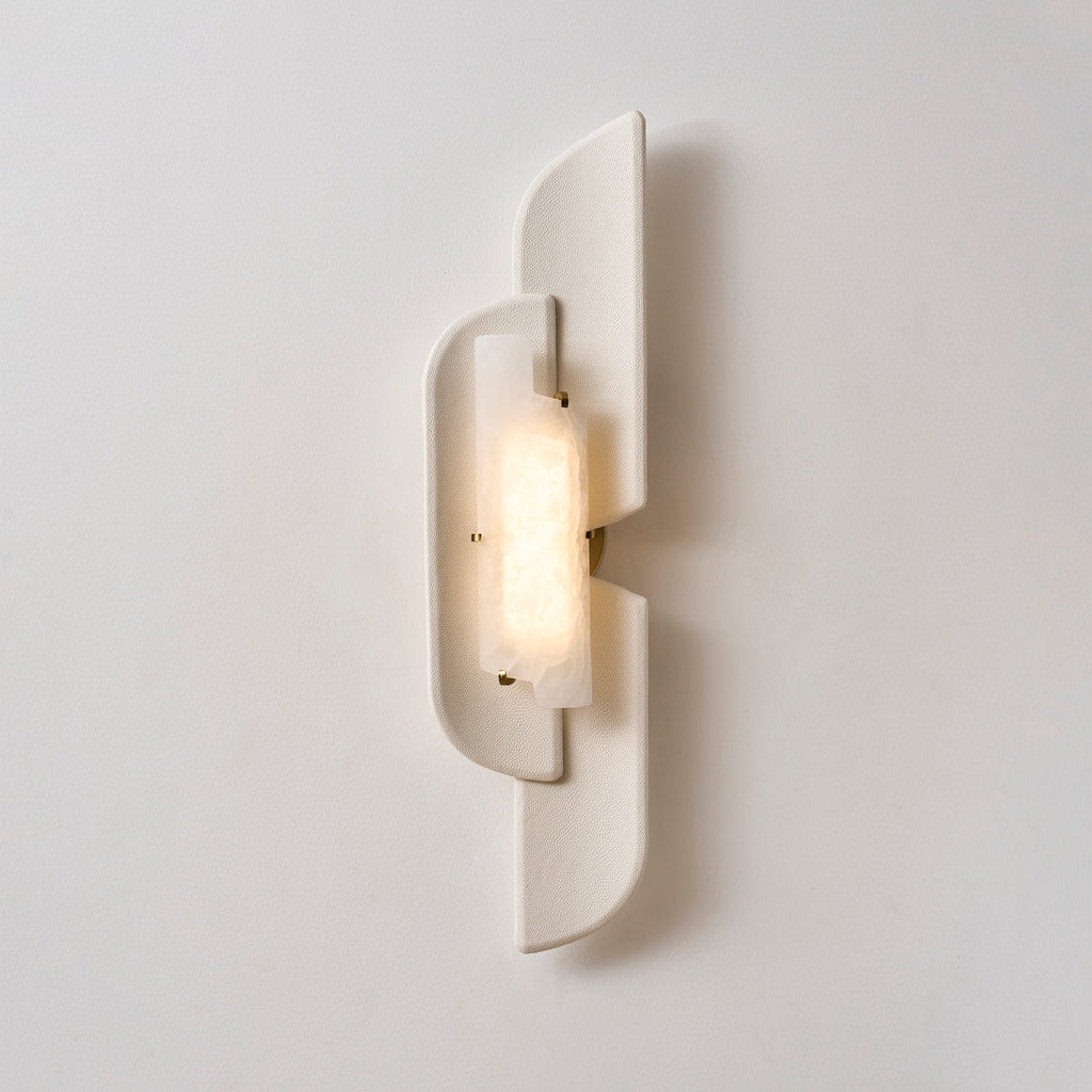 Front view of a lit Clérachic wall lamp, its alabaster glowing warm inside the pale, smooth-edged panels.