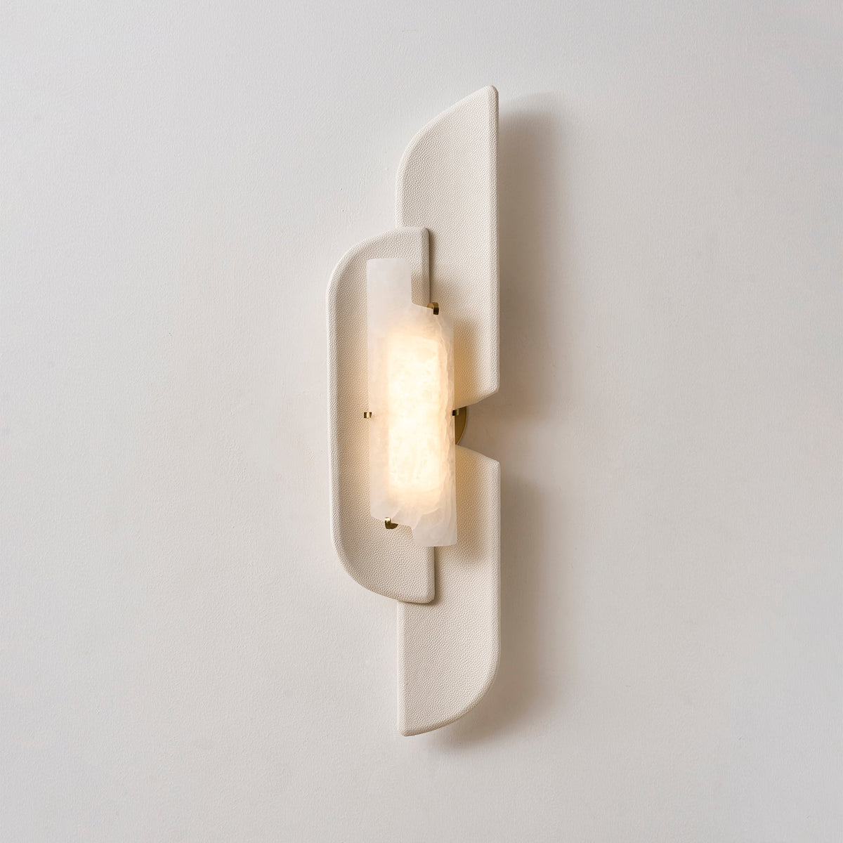 Front view of a lit Clérachic wall lamp, its alabaster glowing warm inside the pale, smooth-edged panels.